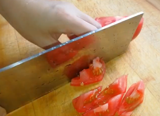 然后准备好的西红柿切成滚刀块,再把清洗干净的鱼也切一下,先从前边切