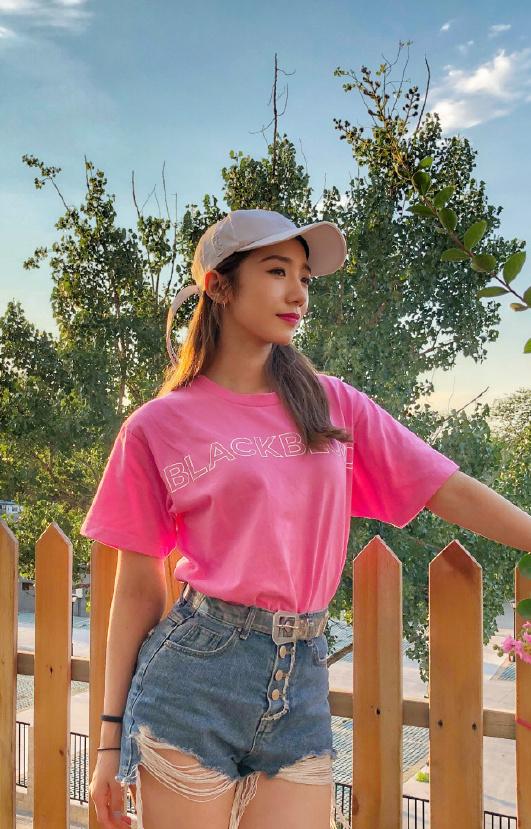 夕阳下的她身着粉色t恤和高腰热裤搭配时下大热单品棒球帽,可以说是潮