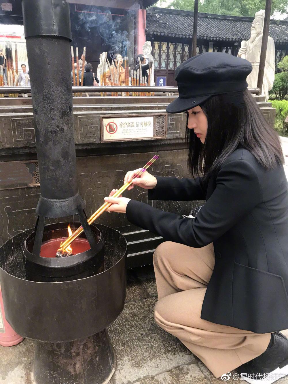 皮肤依旧很白皙透亮,手上拿着3支香正在点燃,聚精会神的表情也
