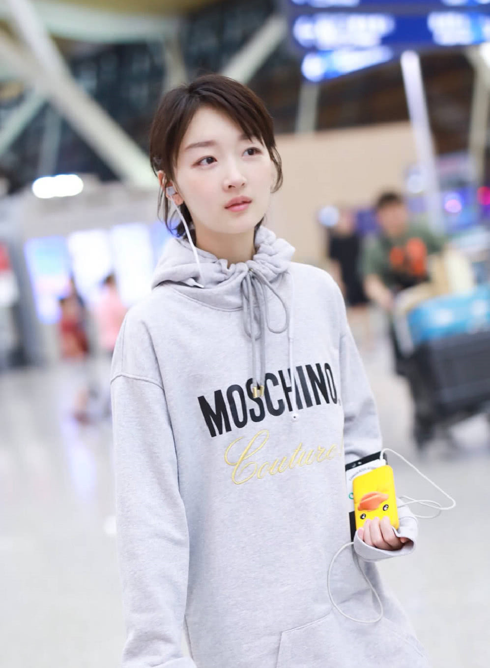 周冬雨现身机场,灰色连帽卫衣配妈妈的高跟鞋,小黄鸭手机壳瞩目