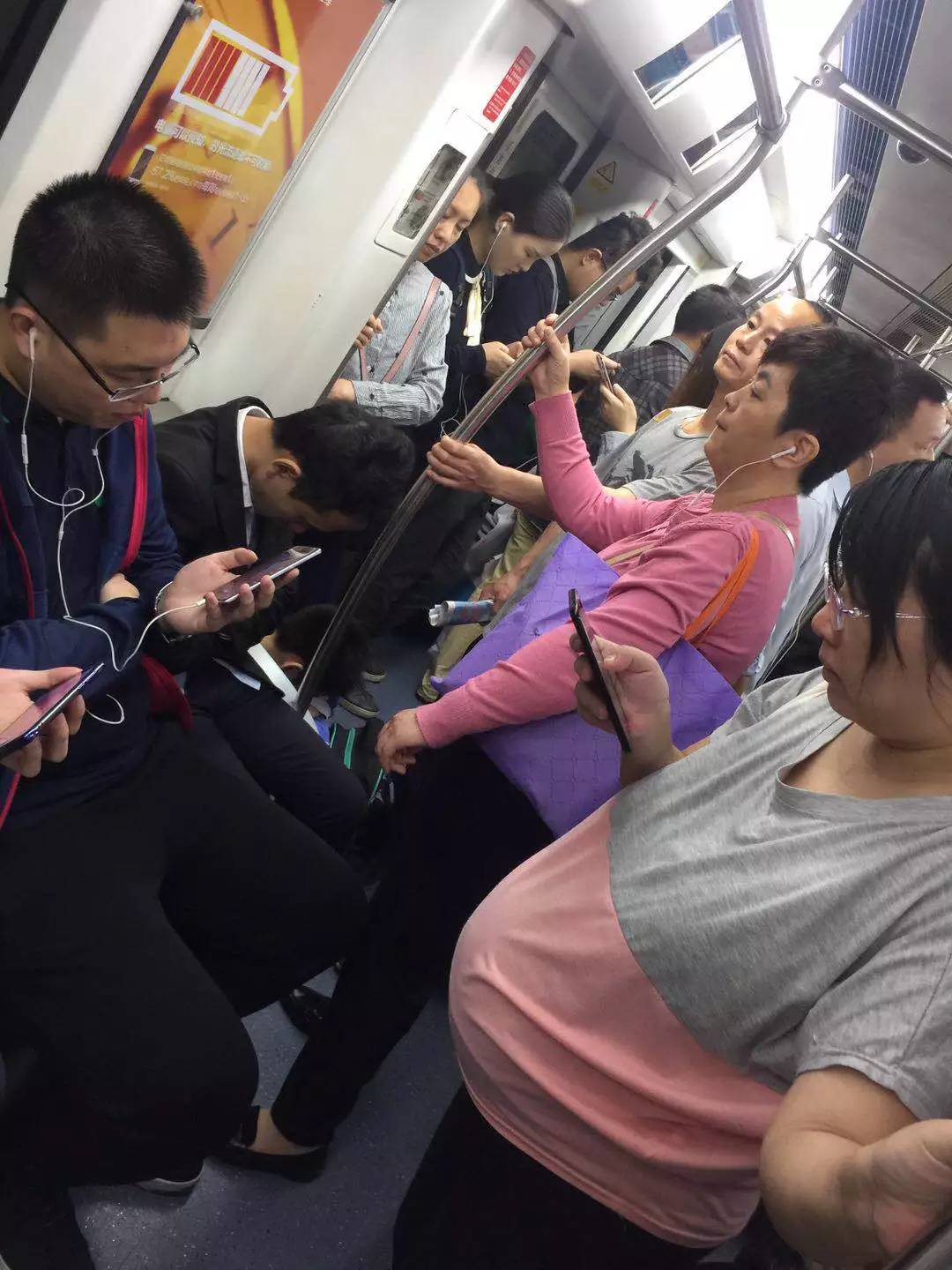 女士优先车厢里,坐着玩手机的男士和站着看手机的孕妇