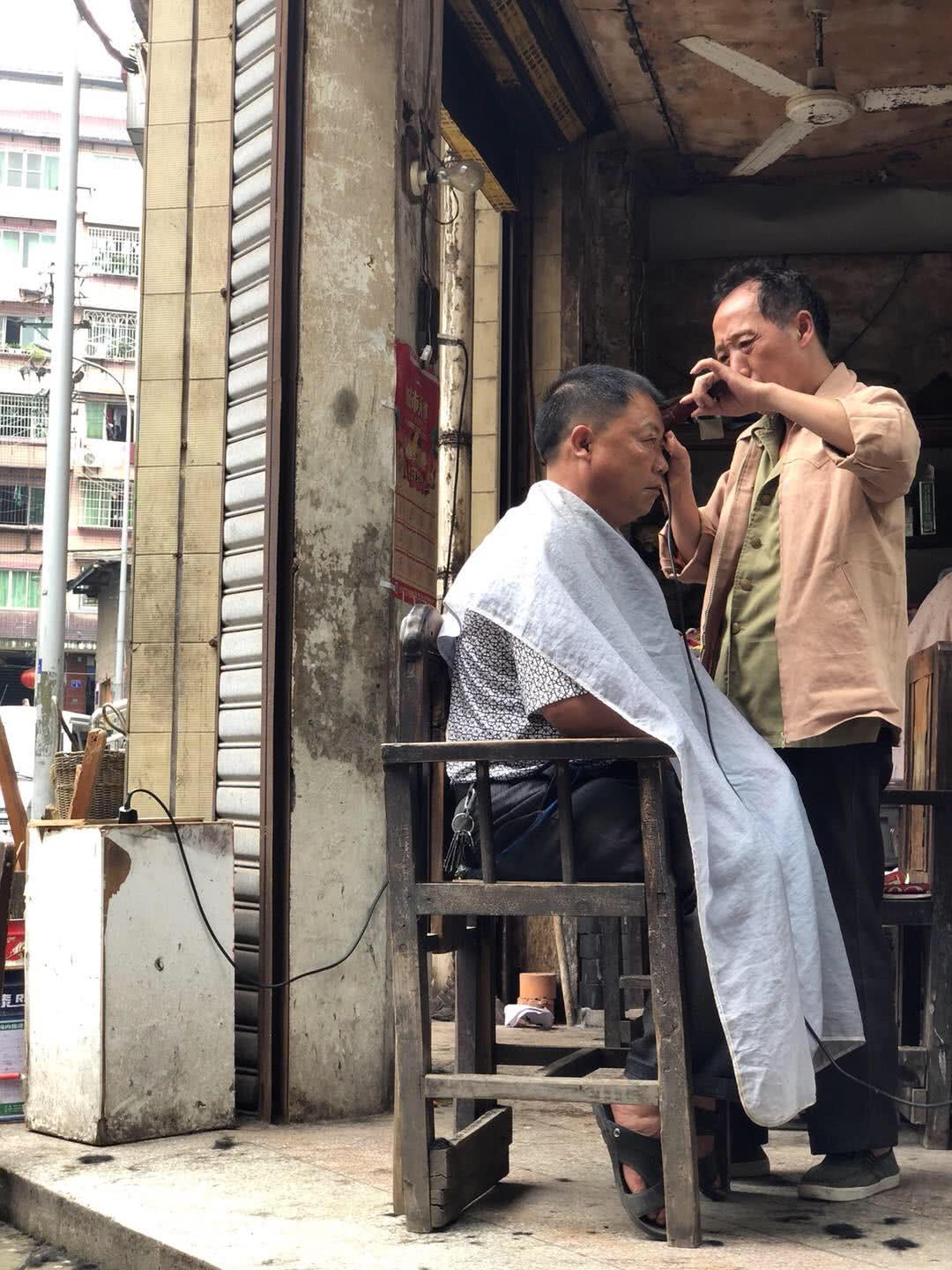 这家路边的理发摊没有发廊里的窗明几净,也没有吹焗染烫的服务.