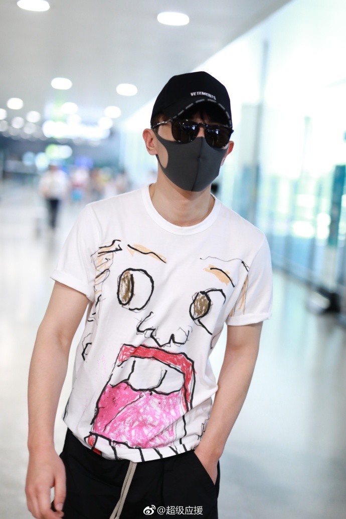 邓伦白色t恤搭配黑色短裤现身机场遮捂严实,衣服上的图案是亮点