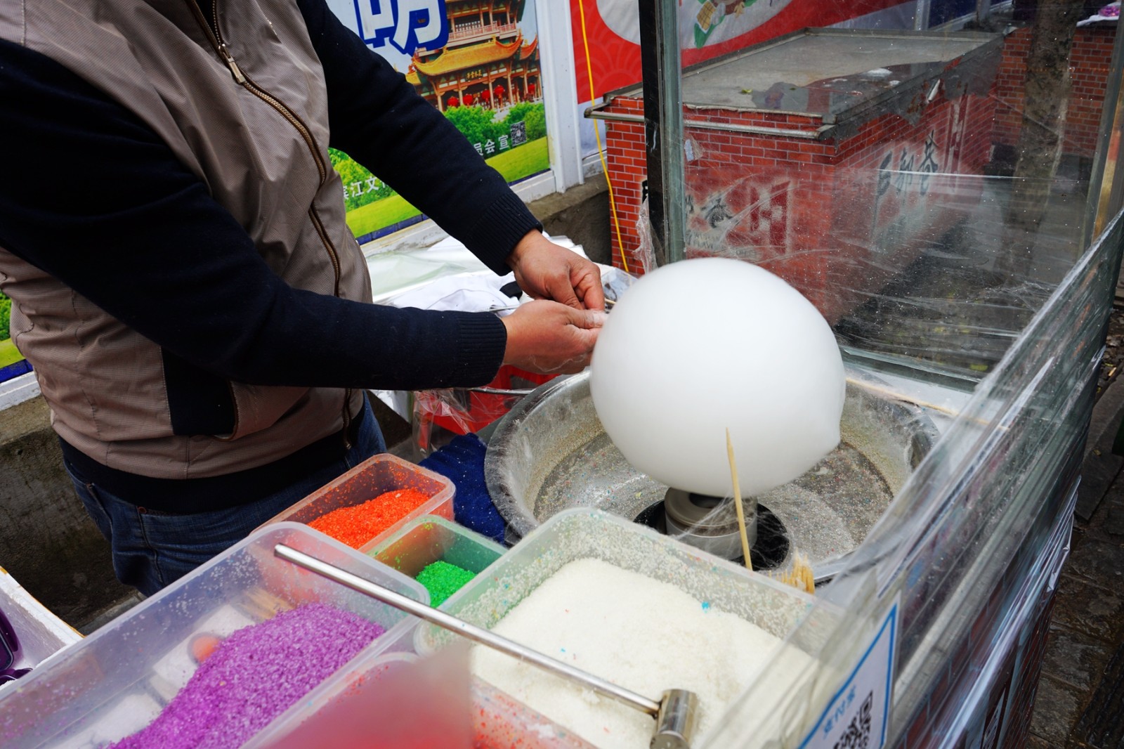 摄影师看到了做棉花糖的店主小哥,正在将做好的棉花糖摆放在摊位上