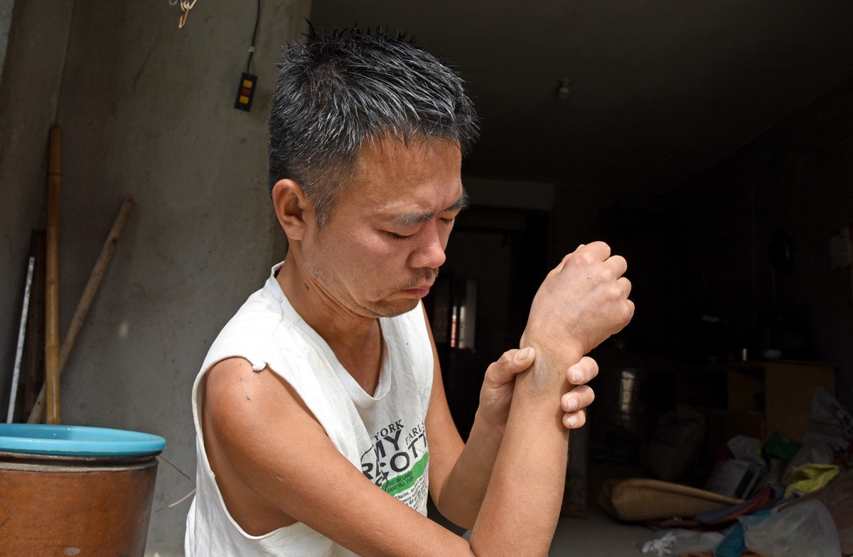 而在人行道的旁,一位骨瘦如柴,身穿背心的男子正努力地往三轮车边挪去