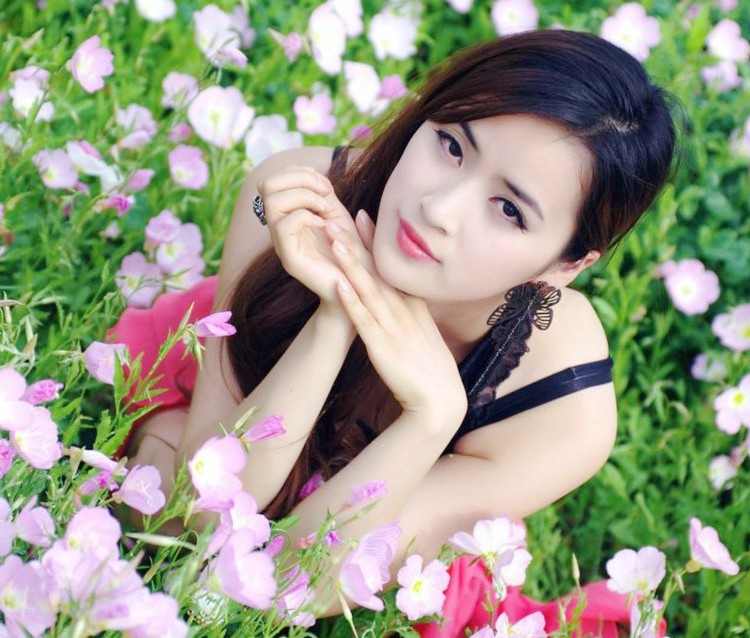 一个人依偎在开满花朵边的清秀美丽姑娘