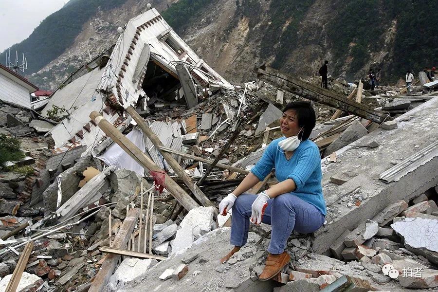 2008年5月23日,老何的嫂子拿着何全寿一家三口的照片走出北川