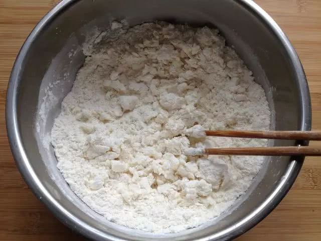 2,先来和面,慢慢把热水(70-80度)倒进面粉里,边倒边用筷子搅拌成絮状