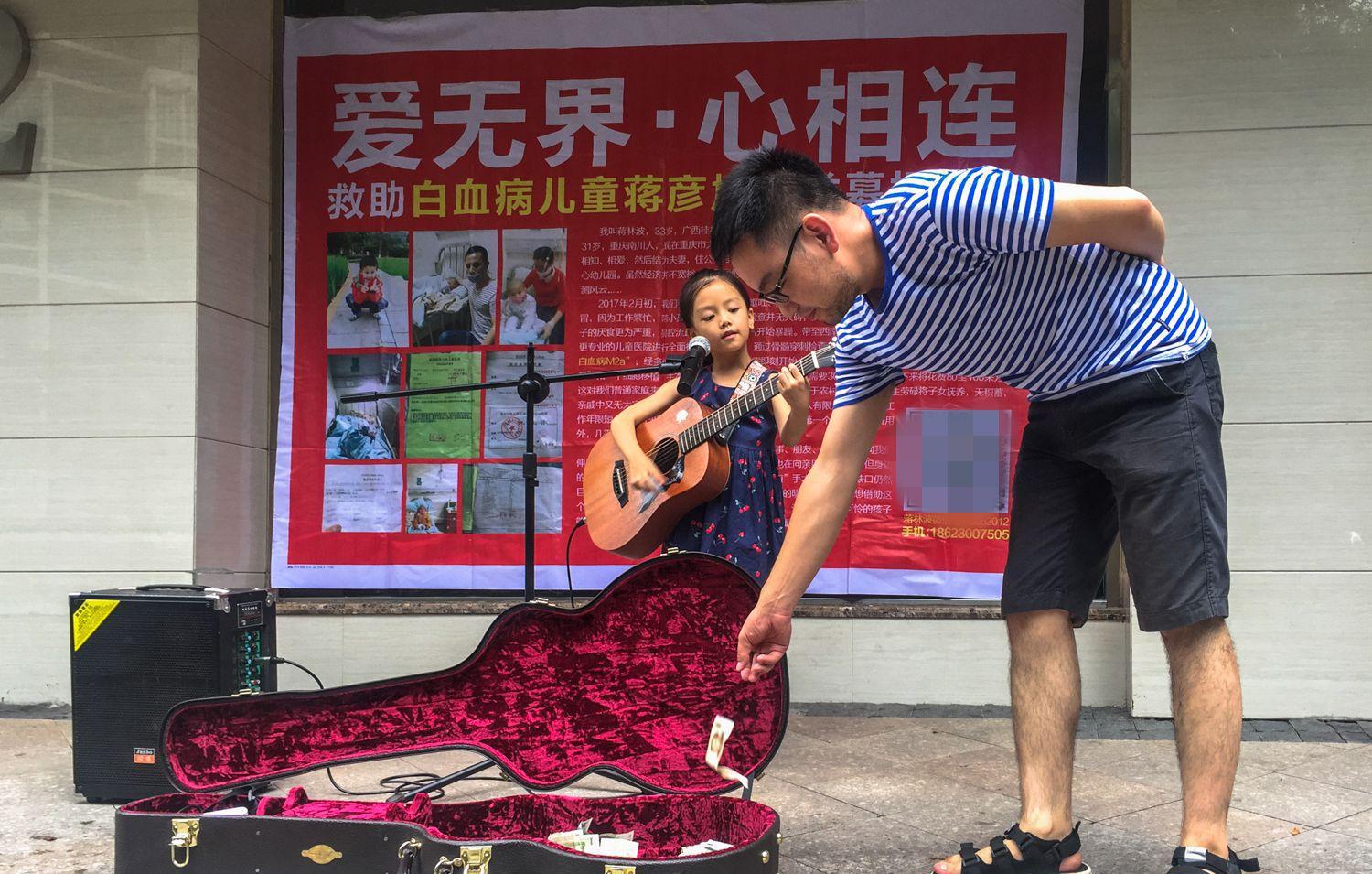 为了给弟弟凑齐手术费用, 7岁小女孩每天在街边卖唱