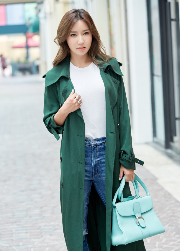 韩雨芹身穿一件白色t恤以及一条蓝色牛仔裤,搭配一件绿色的长款外套