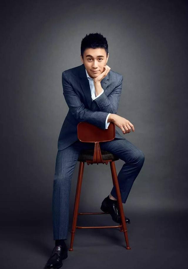 何猷君穿着一身帅气的西装坐在椅子上,俊美绝伦,脸如雕刻般五官分明