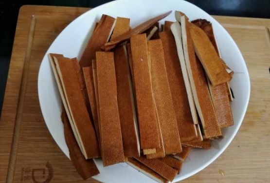 的新鲜豆干,用清水先冲洗一遍,放在案板上,用刀切成宽约一厘米的长条