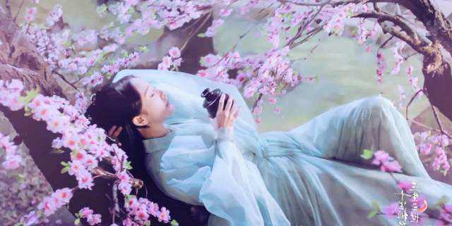 她一袭白衣卧在桃花林里的老树之下饮酒,有种众人皆醉我独醒的韵味,这
