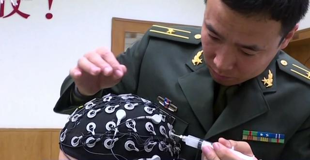 解放军国防科技大学的研究人员对脑控头盔进行认真的调试工作.