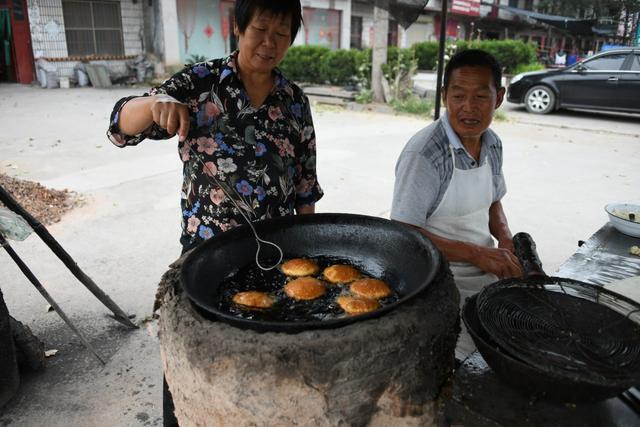 今年60多岁的张大爷正和老伴在油锅前炸糖糕,这个摊位他们从79年开始