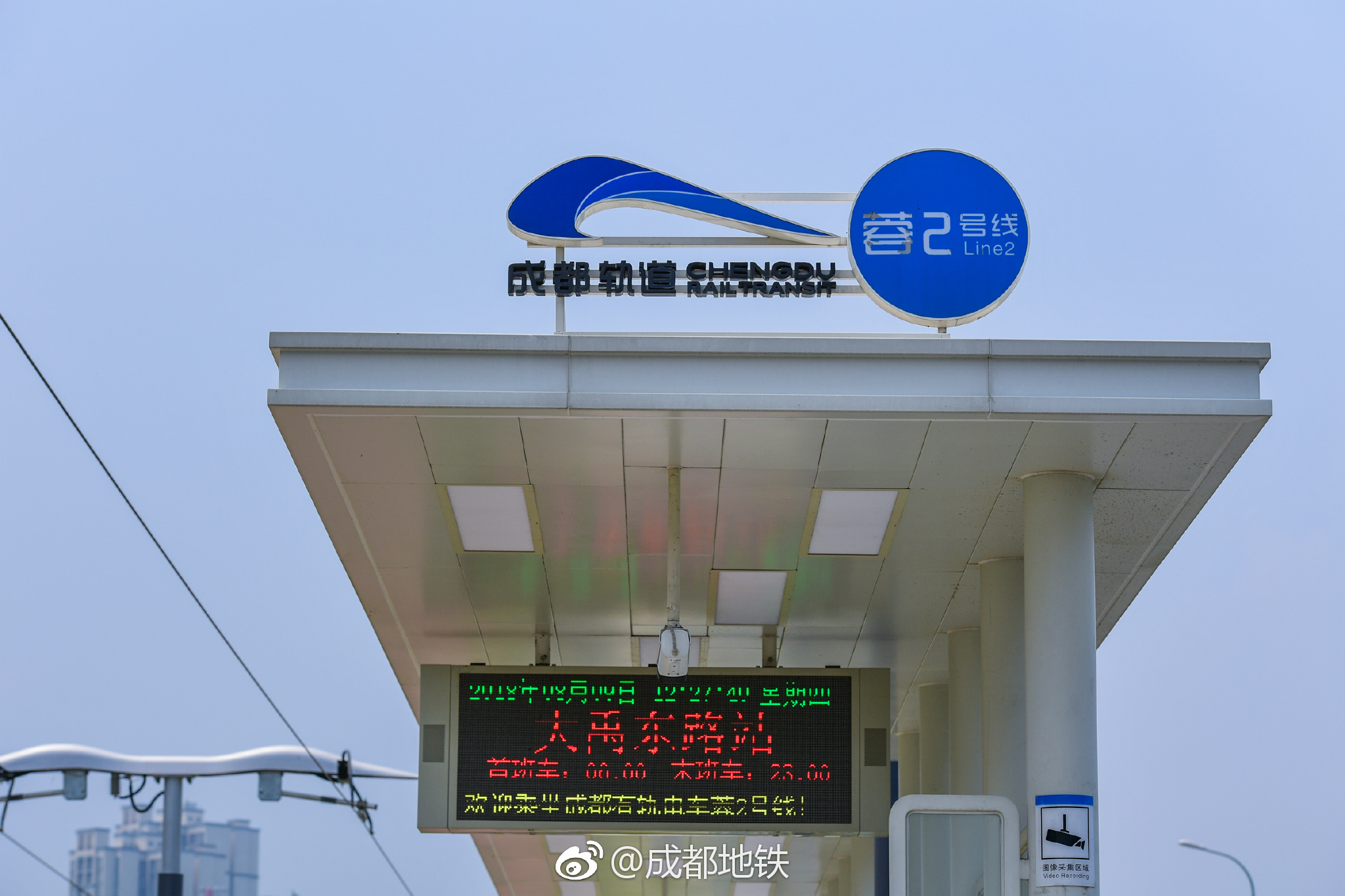 有轨电车蓉2号线车站设置在地面,轨道镶嵌在红色的路面与绿草之间|绿