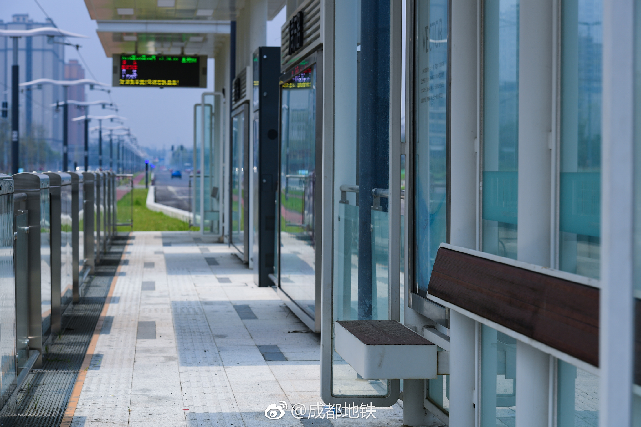 有轨电车蓉2号线车站设置在地面,轨道镶嵌在红色的路面与绿草之间