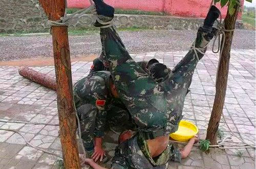 照片中模拟一名深入敌后的侦察兵被俘虏,这名侦察兵被绳子把手脚捆在