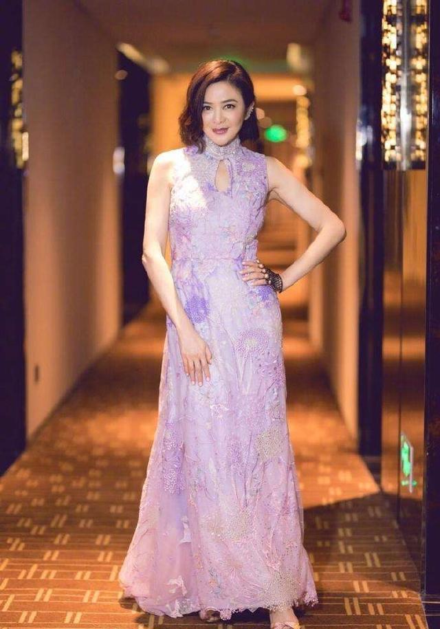 55岁的关之琳身穿着一袭紫色中国风的旗袍,裙身上的设计十分协调,脚上