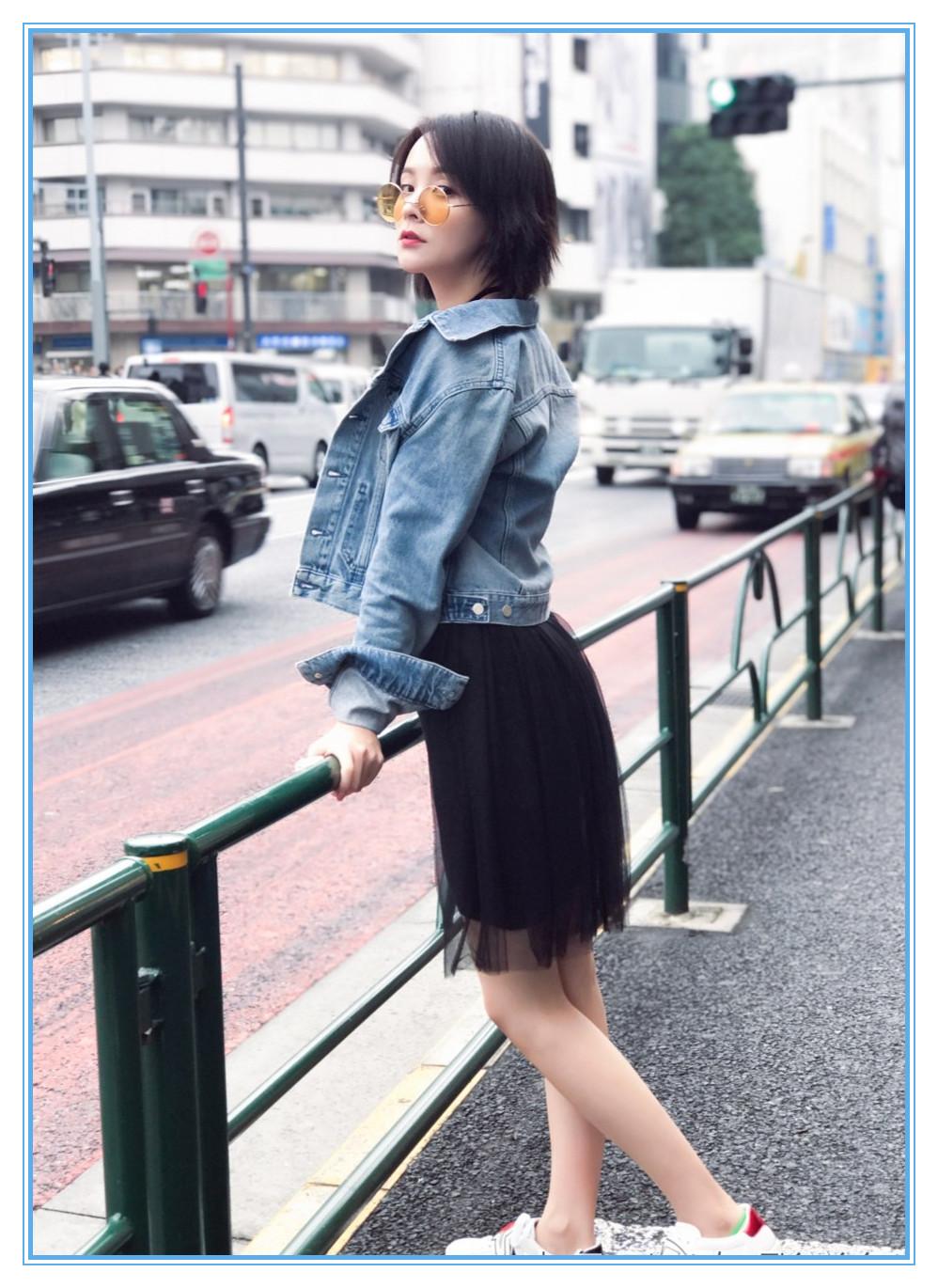 一袭黑色薄纱连衣裙,裙摆盖到膝盖上,外搭一件蓝色牛仔服,,脚踩白色