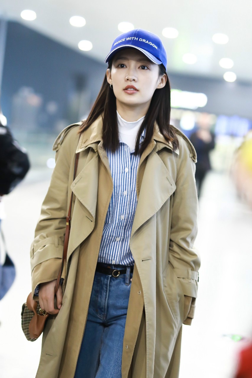 李沁戴蓝色棒球帽穿风衣现身机场,面带微笑挥手打招呼尽显亲和