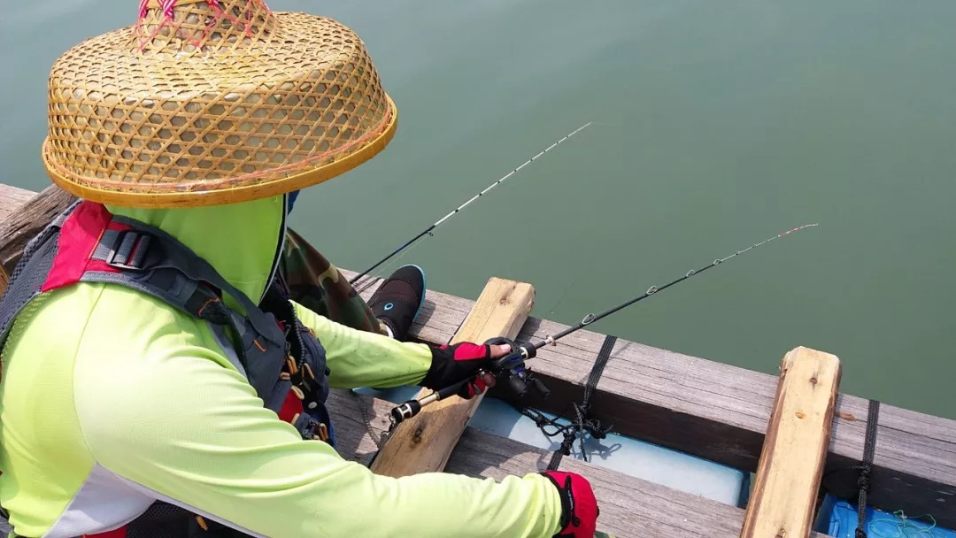 这位钓鱼爱好者很认真在整理鱼杆, 准备钓大鱼