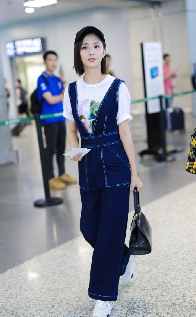 佟丽娅穿牛仔背带裤内搭白t现身机场 笑容迷人露标志性小漩涡