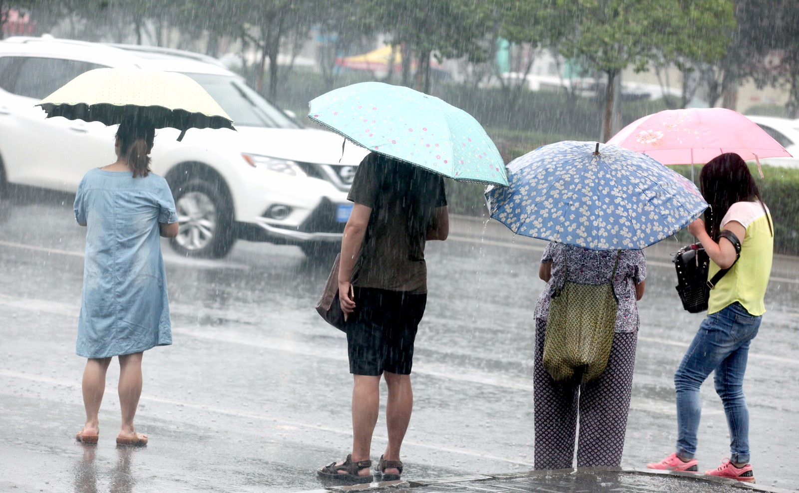 大雨中等待公交车的市民,公交很少,只能在没有遮挡的公交站牌前等车.