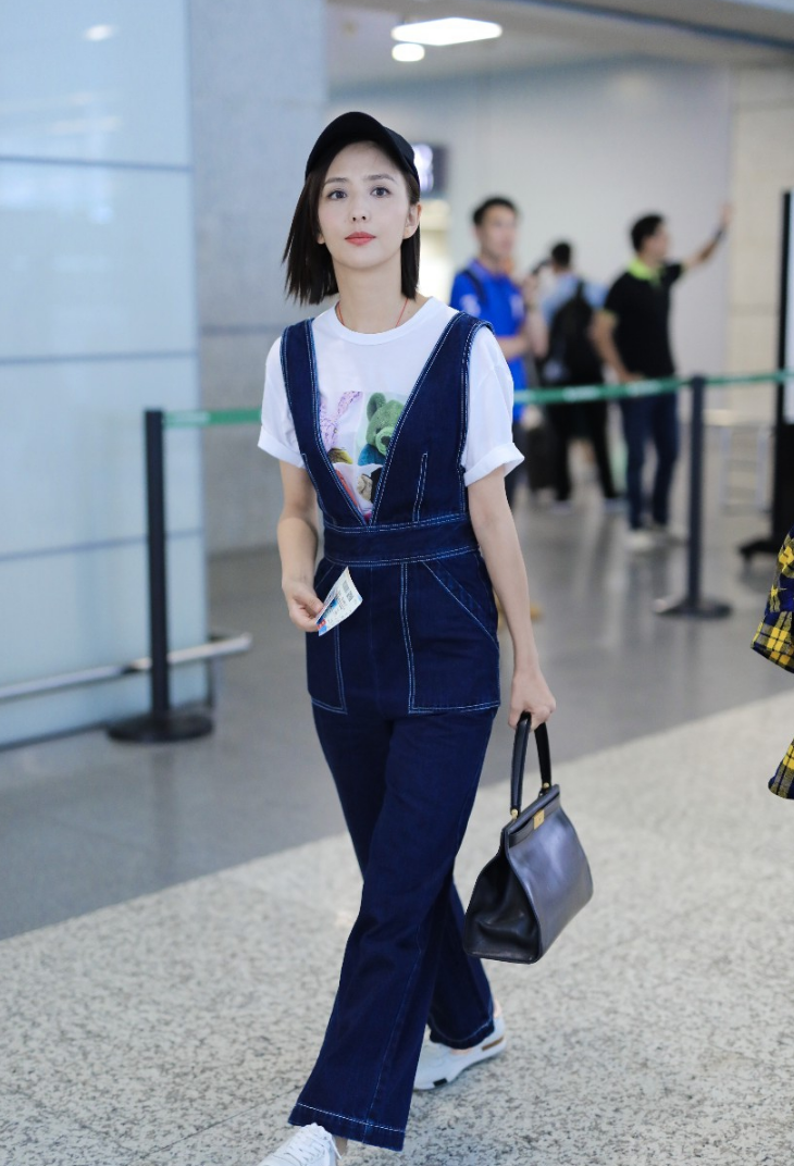 佟丽娅穿牛仔背带裤内搭白t现身机场 笑容迷人露标志性小漩涡
