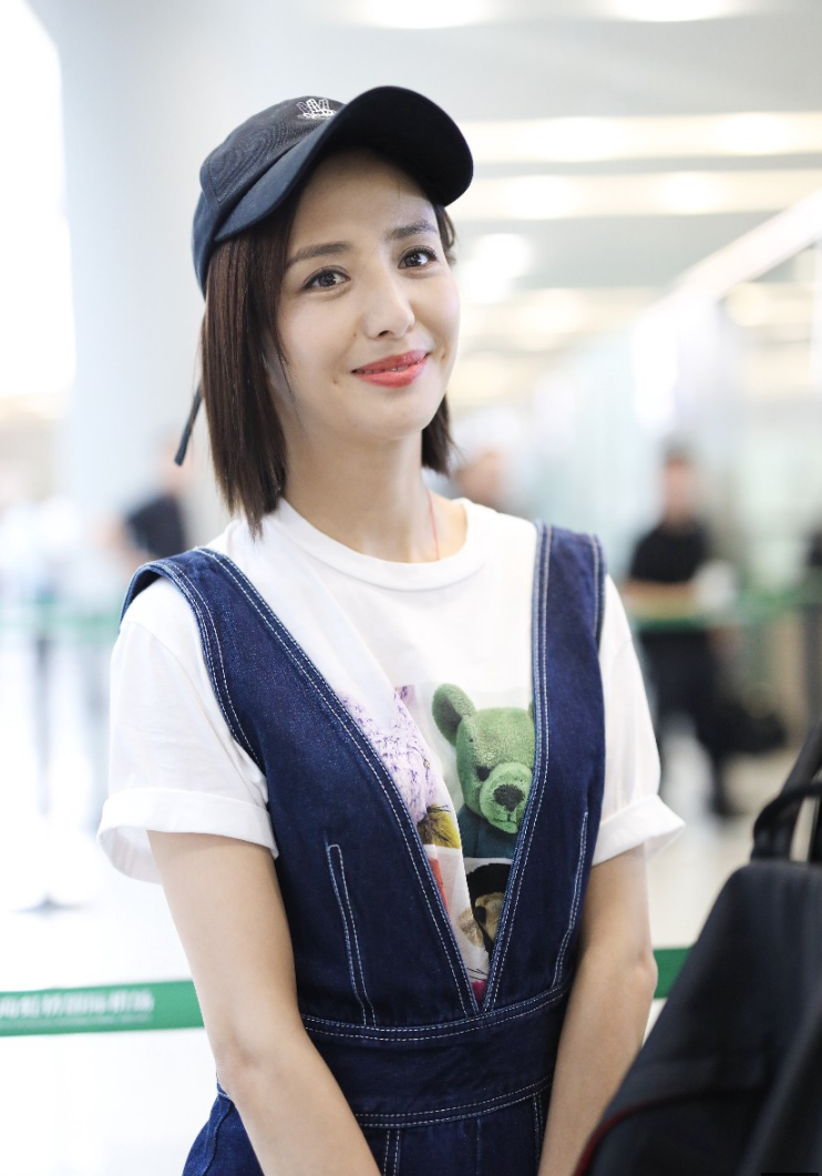 佟丽娅穿牛仔背带裤内搭白t现身机场 笑容迷人露标志性小漩涡