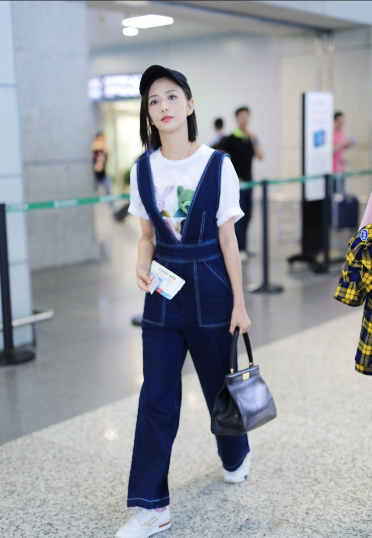 佟丽娅穿牛仔背带裤内搭白t现身机场 笑容迷人露标志性小漩涡