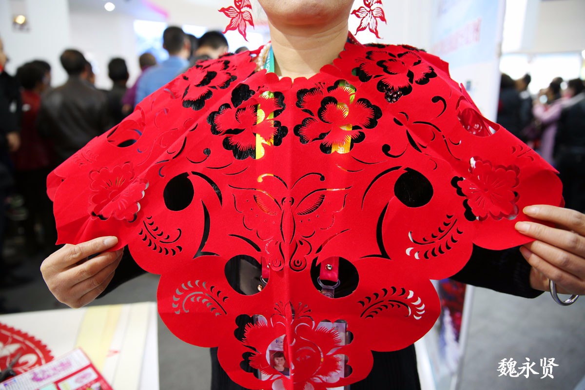 杨凌农高会上剪纸大姐亮了:穿戴上自己剪的帽子衣服耳环吸引人