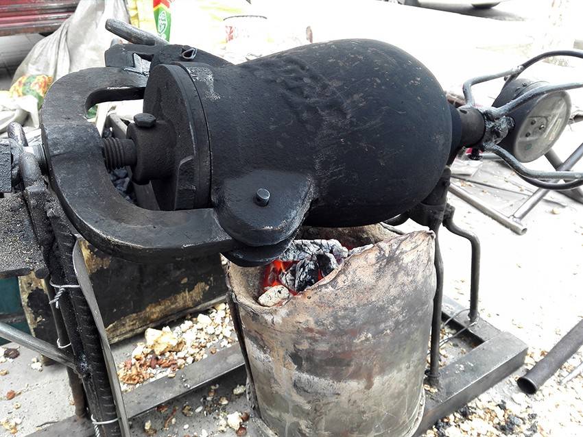 这种老式爆米花机原始的还是手摇式的,师傅一边拉着风箱一边摇动着.