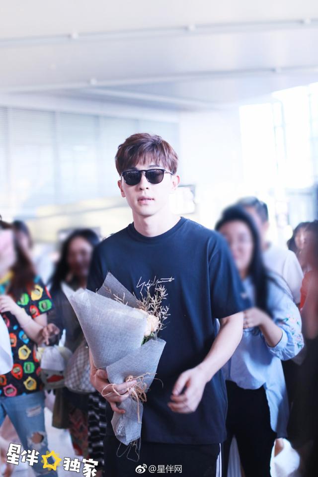 邓伦低调现身上海机场手拿捧花心情超好