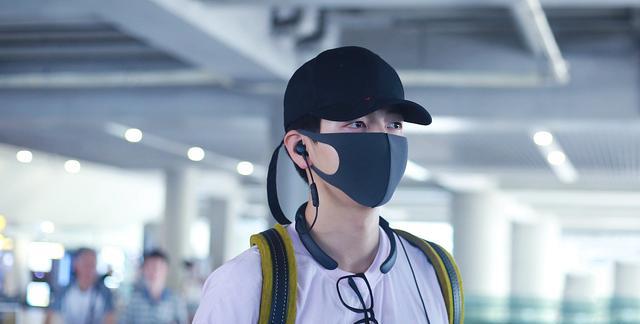 胡夏戴着黑色帽子和深灰色口罩,上身穿着白色小熊t恤,下身穿着黑色