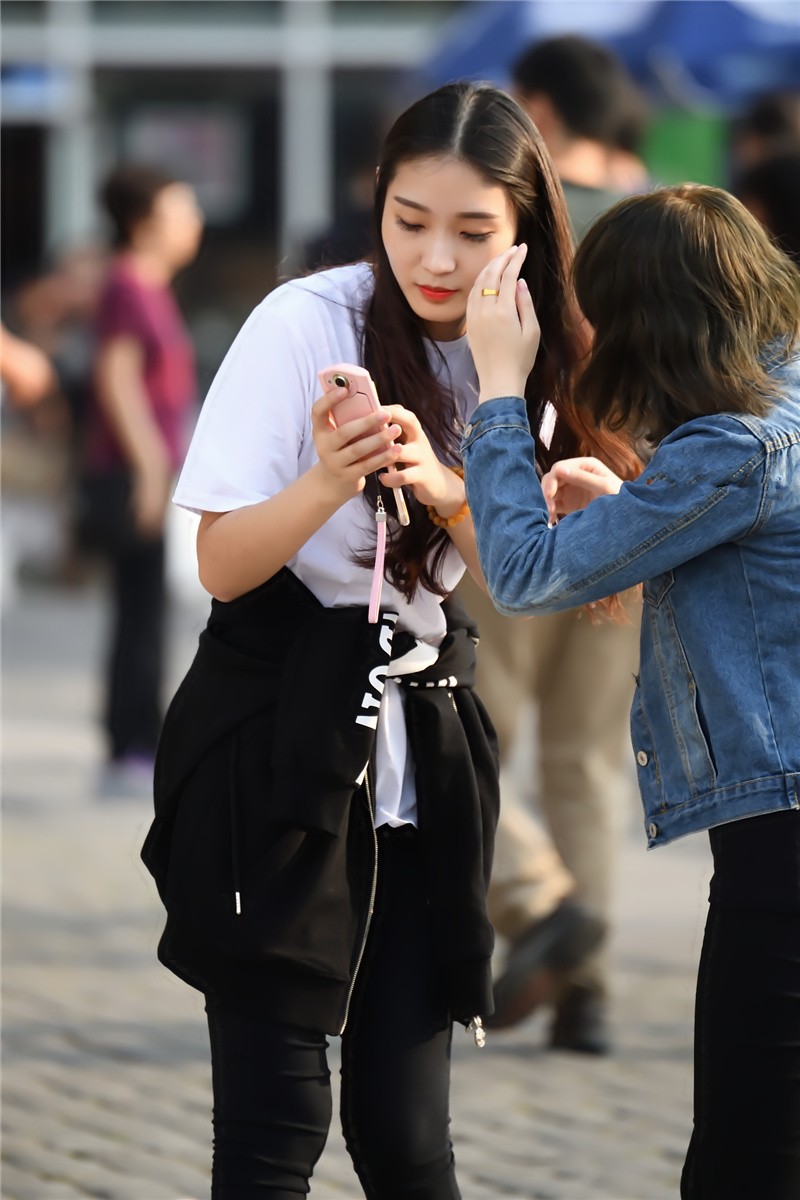 路人街拍外套扎在腰间的长发美女和闺蜜游戏玩的不亦乐乎