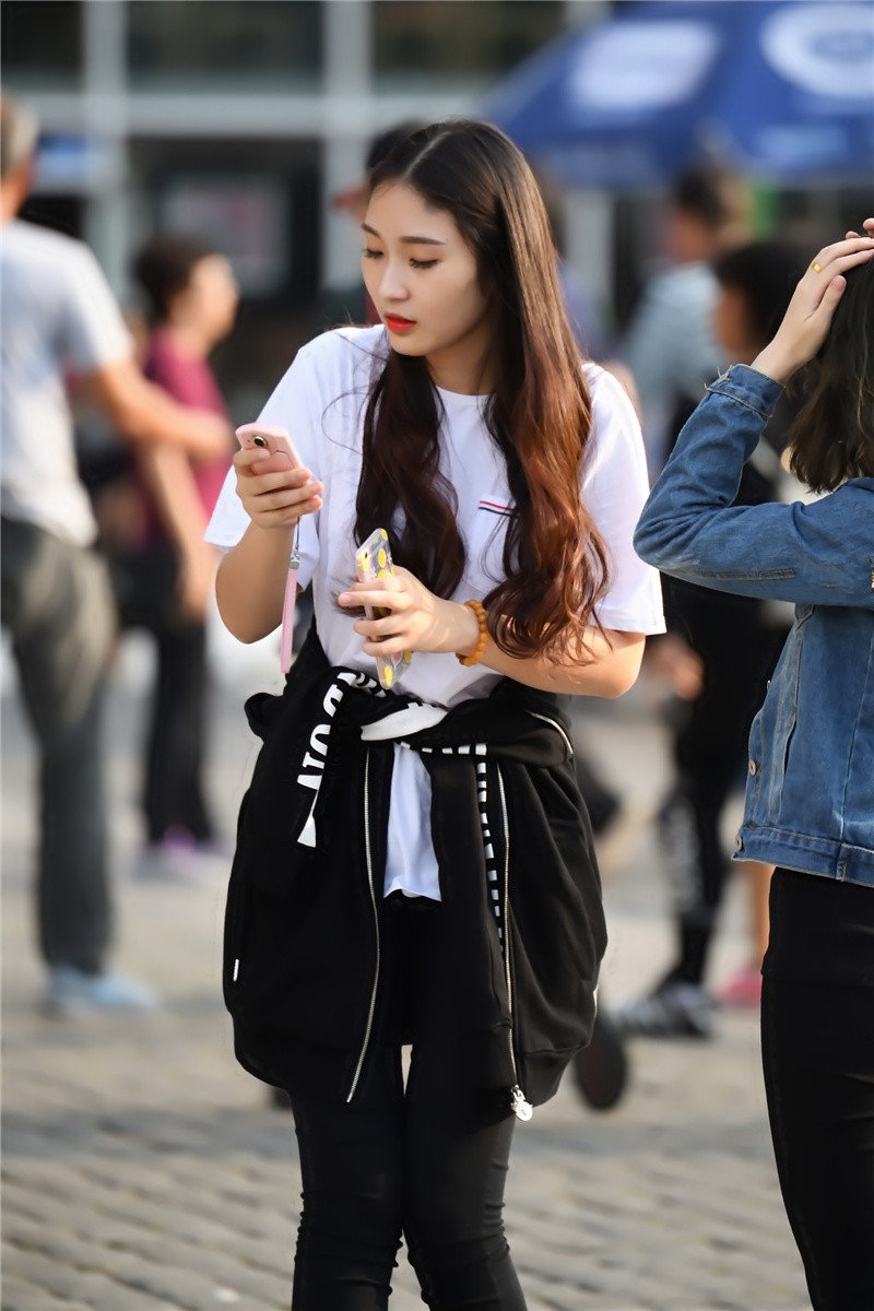 路人街拍外套扎在腰间的长发美女和闺蜜游戏玩的不亦乐乎