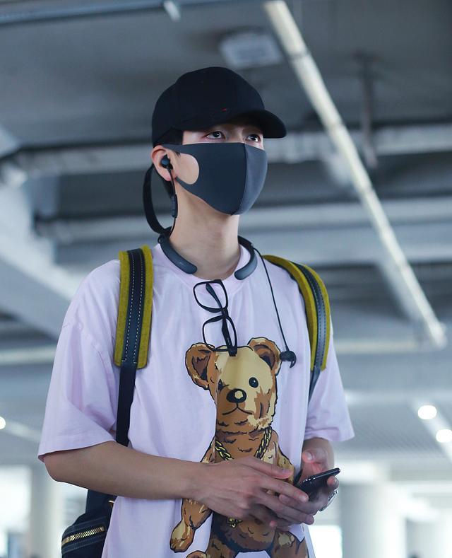 胡夏戴着黑色帽子和深灰色口罩,上身穿着白色小熊t恤,下身穿着黑色