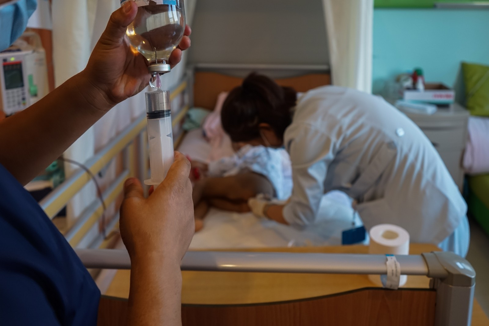 图为满峻宇爸爸在帮助护士给小俊宇冲洗肠道,每天用生理盐水冲洗一次