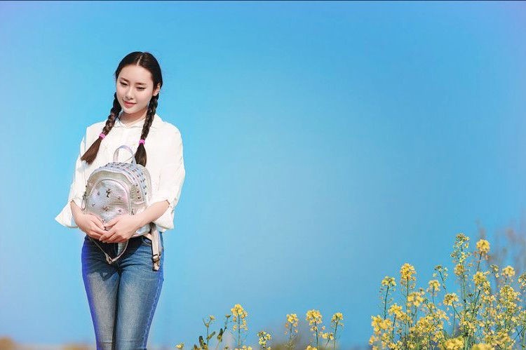 一个依偎在金黄色油菜花边的小辫子姑娘!