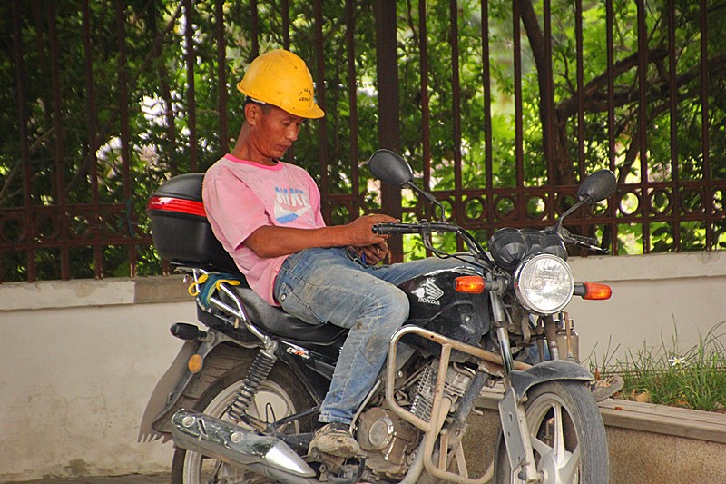 一位民工午饭后坐在摩托车上乘凉.