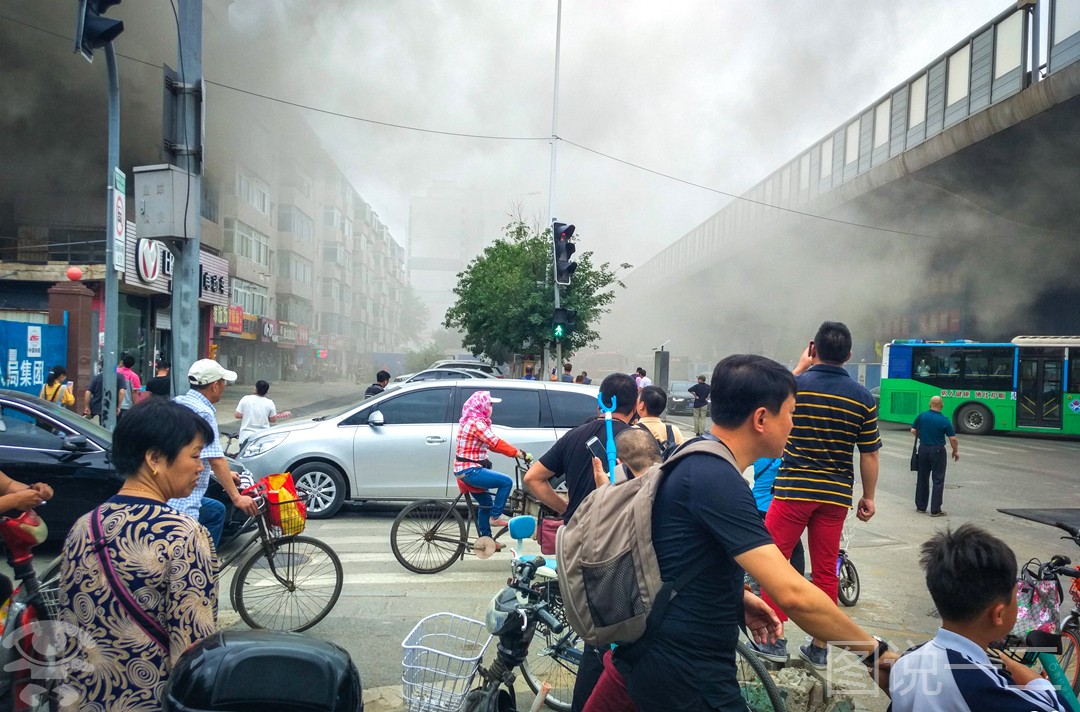 住宅楼起火男子爬楼顶看热闹,下面拍照小伙:你要成烤肉啦!