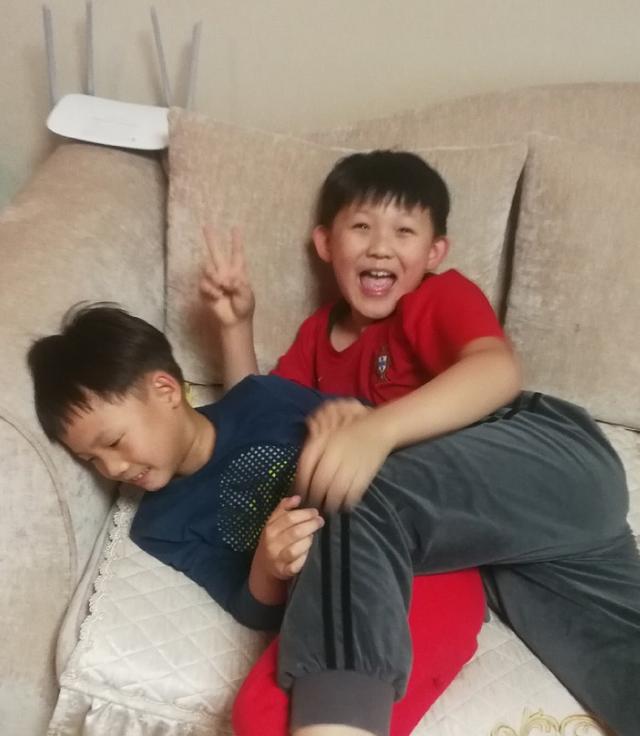 穿着红色上衣的正是杨志刚的小儿杨子睿,一边打闹也不忘对着镜头比"