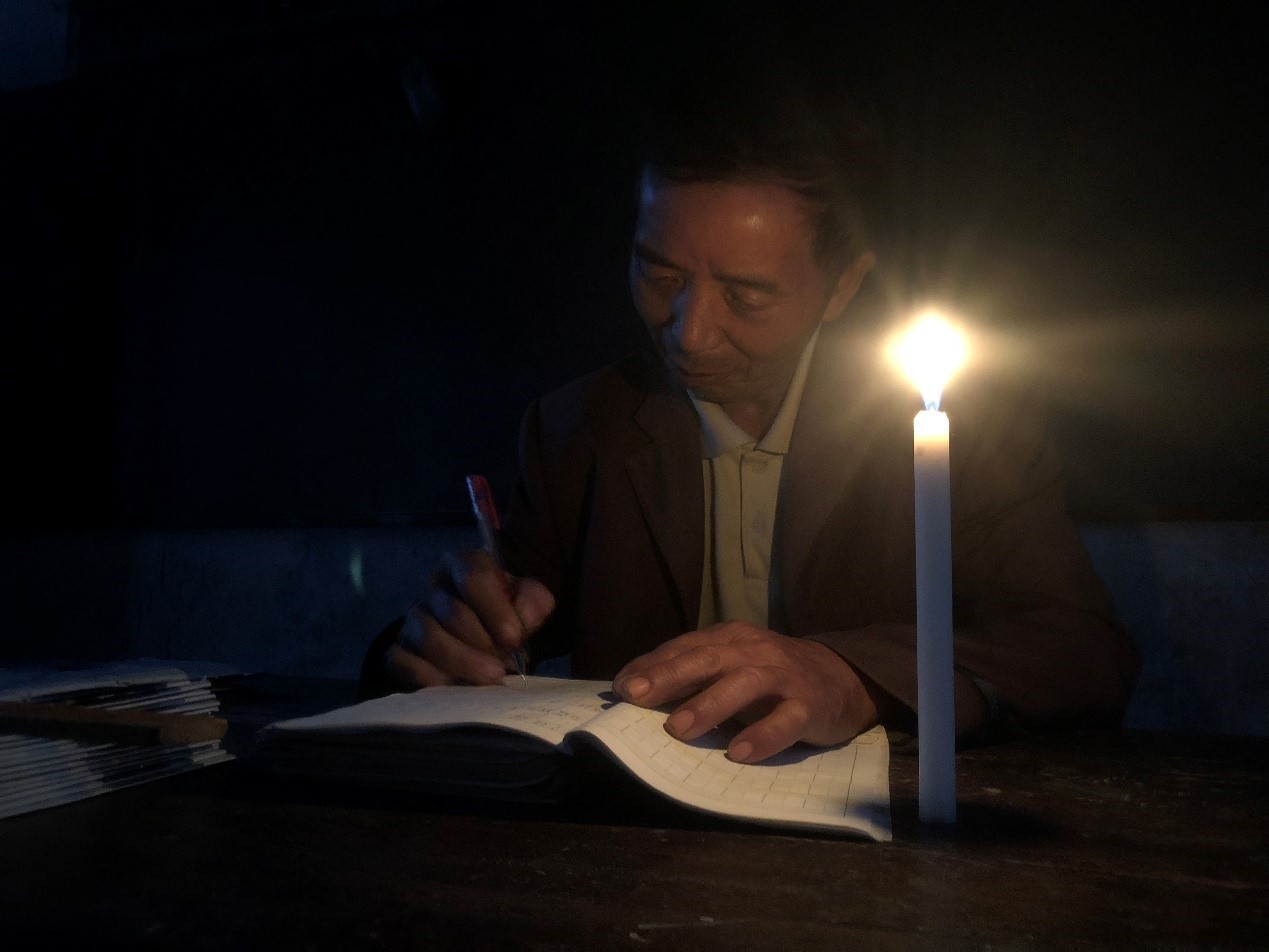 烛光中批改作业的老师