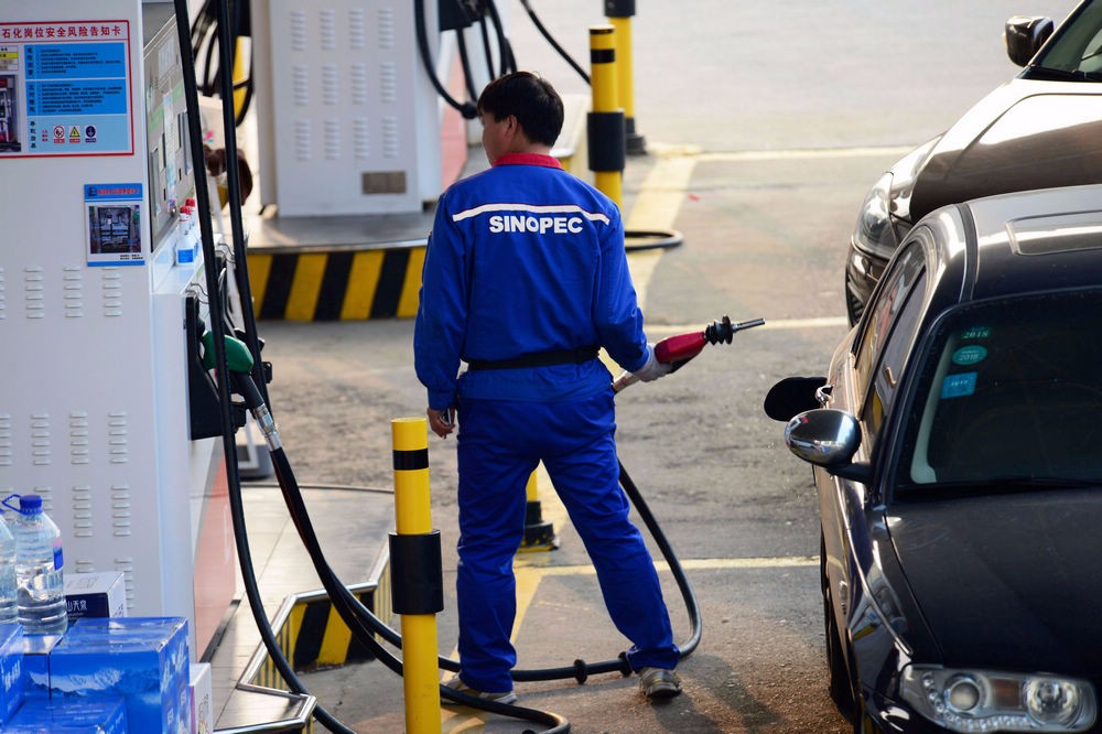 图为加油站工作人员在给前来的车辆加油.
