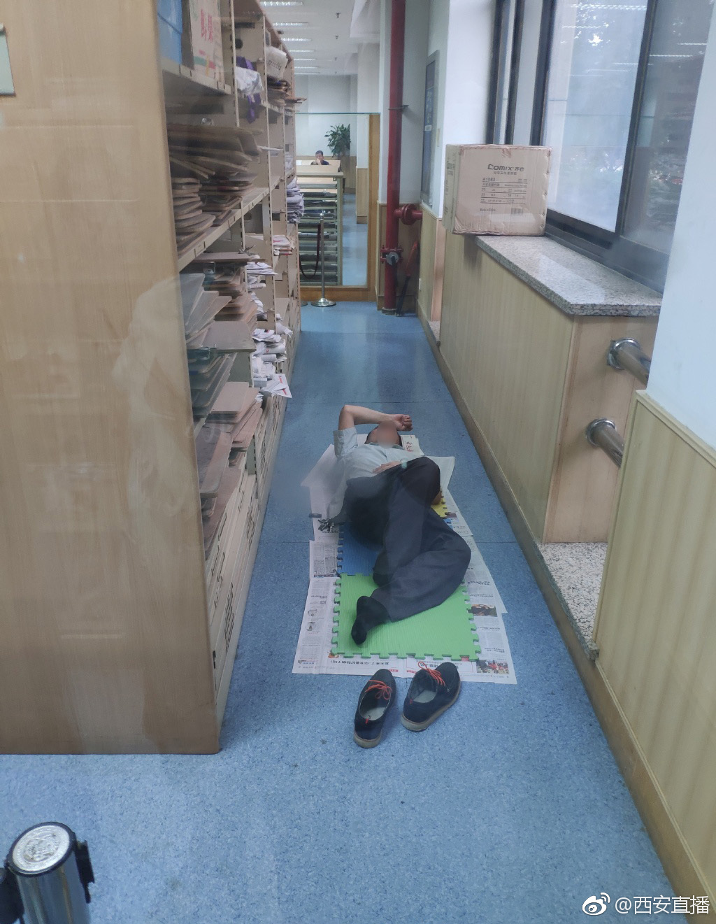 图书馆内:男子脱鞋躺在地上阅读报纸