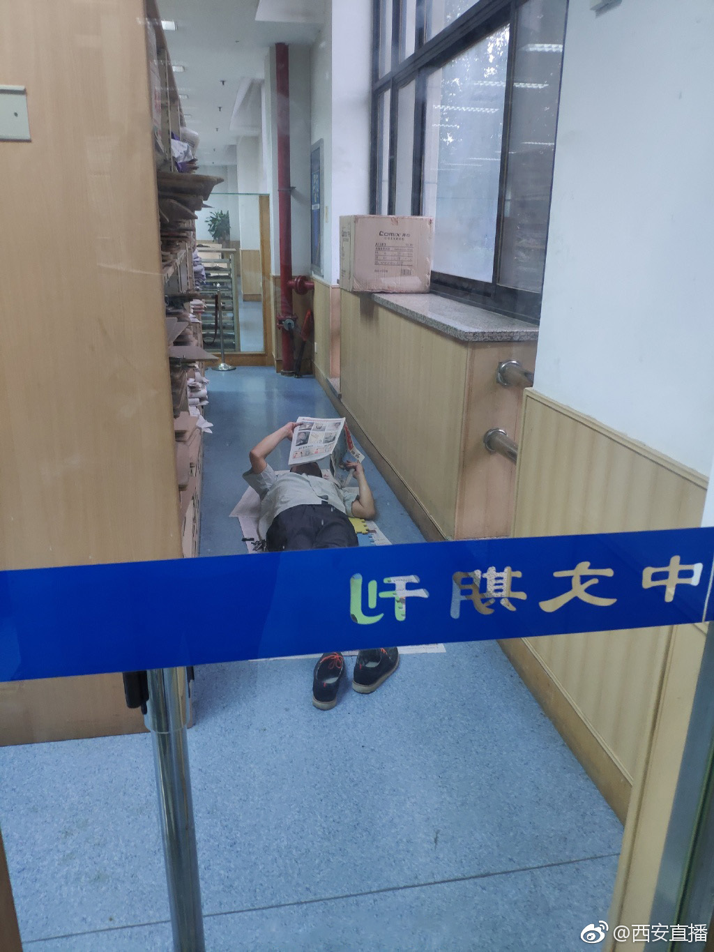 图书馆内:男子脱鞋躺在地上阅读报纸
