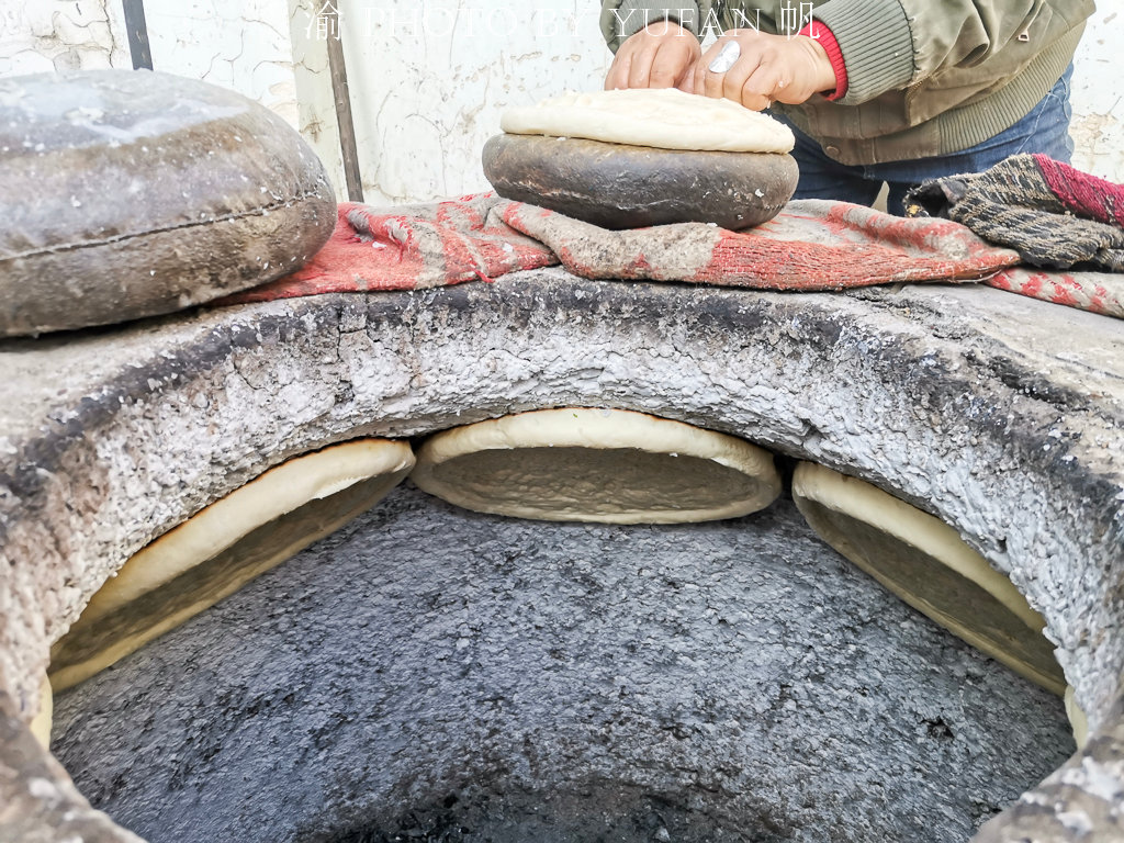 在新疆向维族大叔学习做馕工艺,看着容易做却难,几次掉在馕坑中
