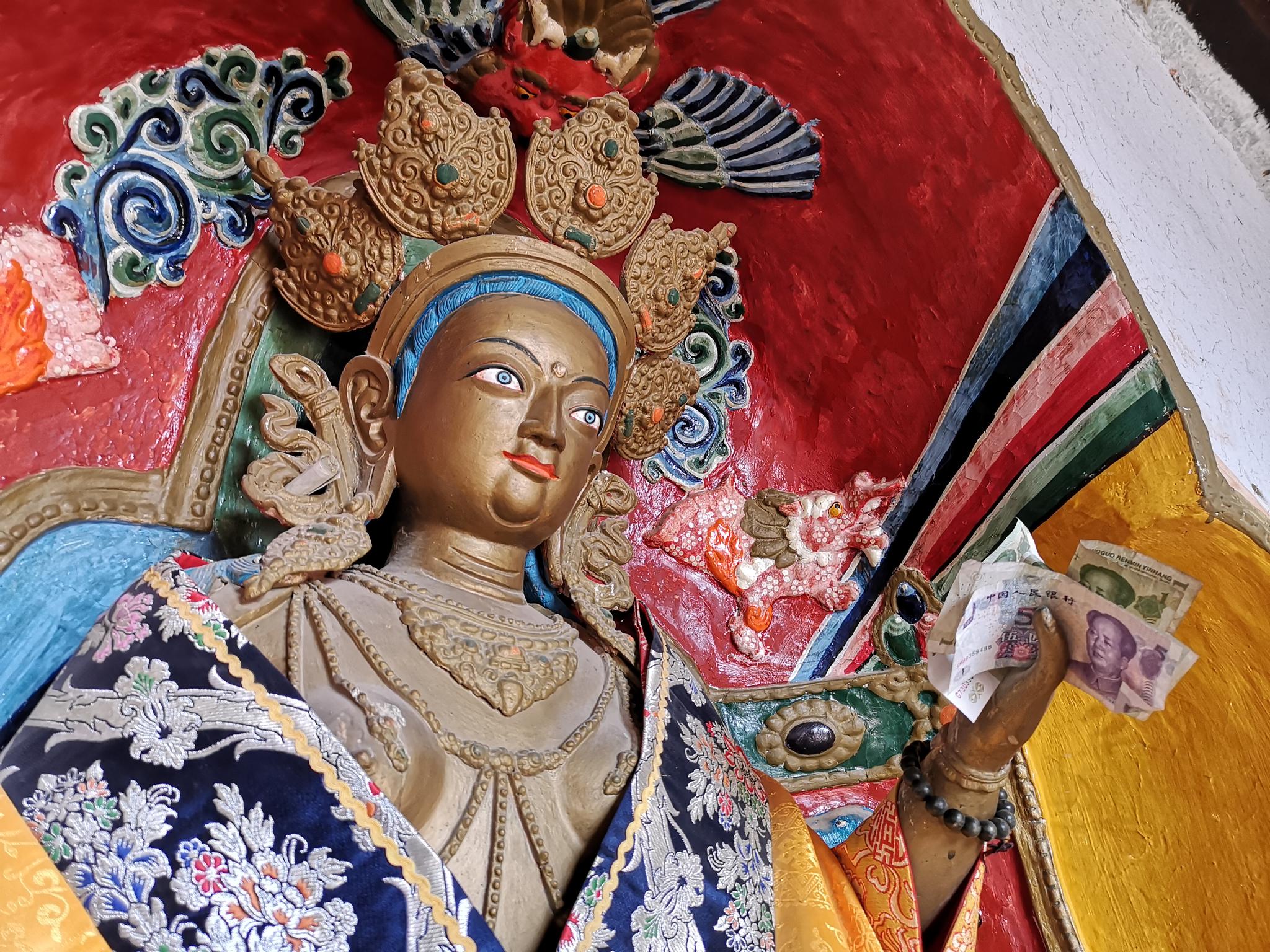 张掖马蹄寺石窟,游客塞在佛像手上的钱