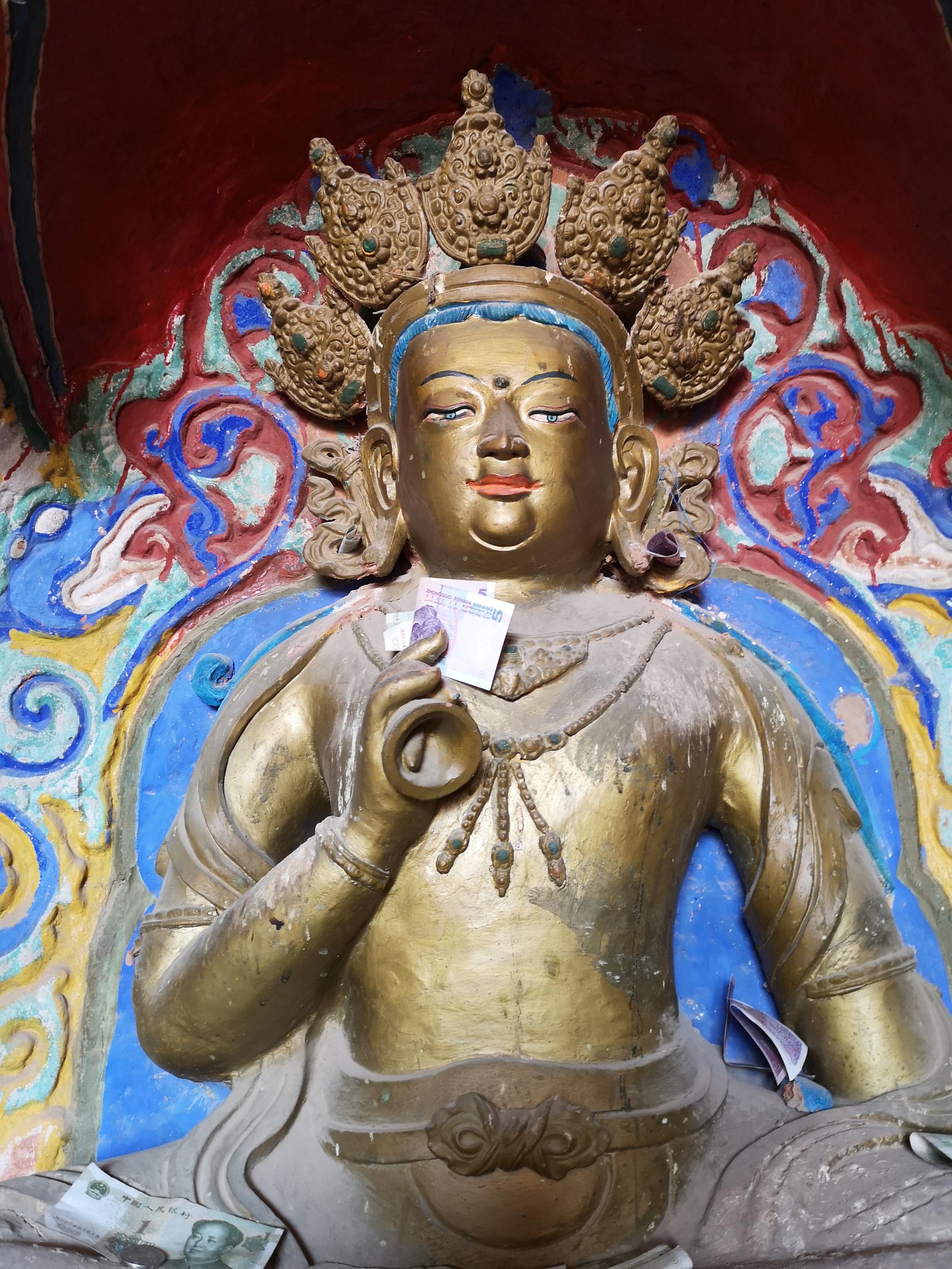 张掖马蹄寺石窟,游客塞在佛像手上的钱